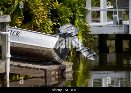 Rear End Of Small Fishing Boat with Motor Beached on a Wooden Dock Stock Photo