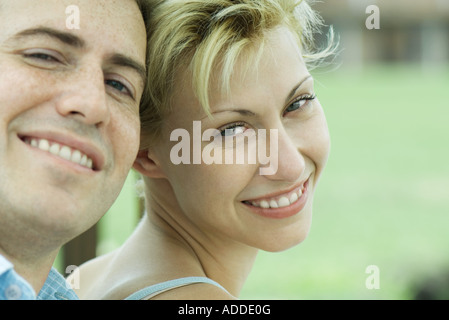 Couple leaning heads together, smiling at camera, close-up Stock Photo