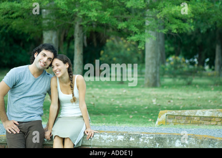 Couple sitting outdoors, heads together, smiling Stock Photo