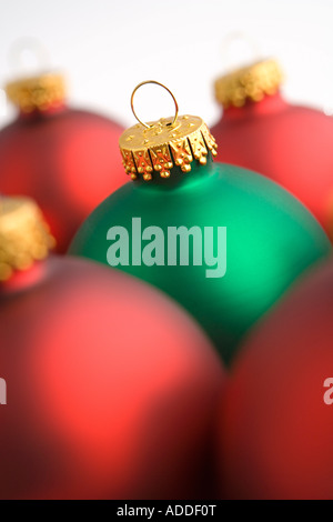 Closeup of one green Christmas tree bulb ornament among red bulbs on white background studio portrait Stock Photo