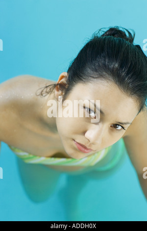 Young woman in pool wearing bikini, looking up at camera, close-up, high angle view Stock Photo