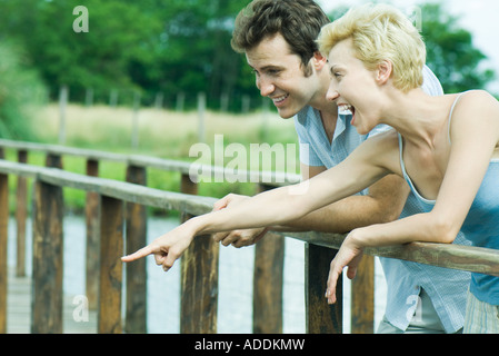 Couple standing on foot bridge, woman pointing Stock Photo