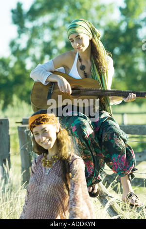 Young hippie women, one playing guitar Stock Photo