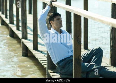Businessman on wooden footbridge over lake, looking away Stock Photo