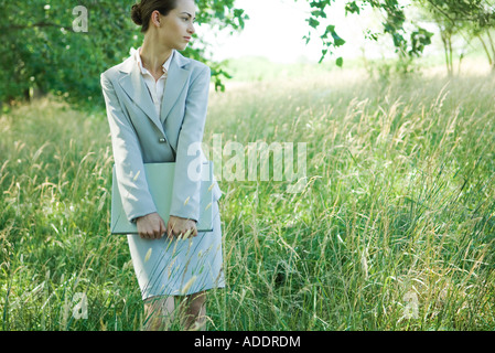 Businesswoman standing in field, holding laptop Stock Photo