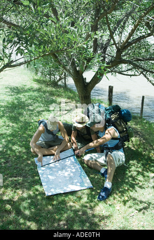 Hikers sitting on ground, looking at map Stock Photo