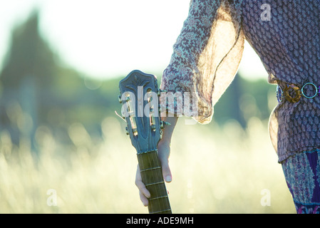 Young hippie woman holding guitar, cropped view of mid section Stock Photo