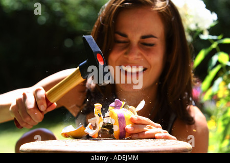 Young woman is robbing a piggy bank with a hammer © Peter Schatz/Alamy Stock Photo