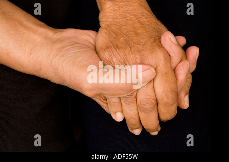 An old asian couple hold hands in a comforting or supporting manner Stock Photo