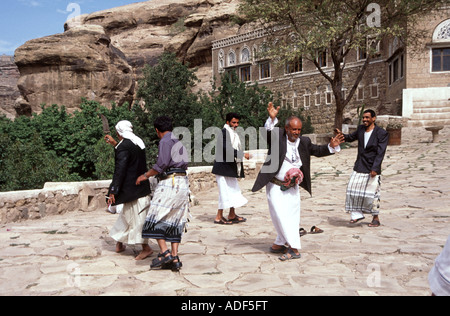 Men doing traditional wedding dance below Dar Al Hajar rock palace Yemen Stock Photo