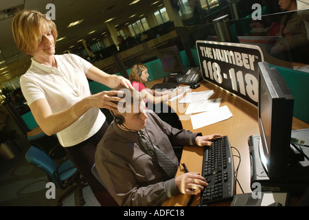 The Number 118 118 Cardiff directory enquiry service call centre staff having Indian head massage in office South Wales UK Stock Photo