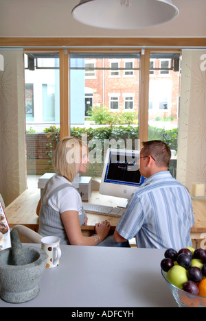 AN IMAC IN USE BY A COUPLE IN THE DINING ROOM AREA OF A CONTEMPORARY STUDIO FLAT UK 2007 Stock Photo