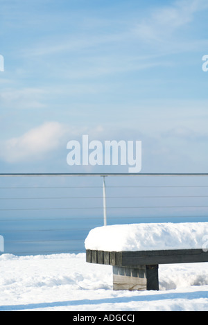 Snow-covered bench overlooking lake Stock Photo