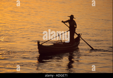 Silhouette of a Burmese boatman rowing on the Irrawaddy river at sunset Burma Myanmar Stock Photo