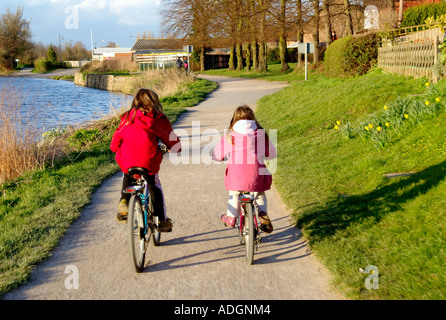 girl children cycling by riverside Stock Photo