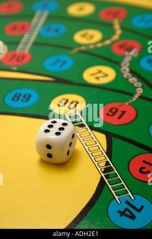 dice on a snakes and ladders board game with player missing Stock Photo