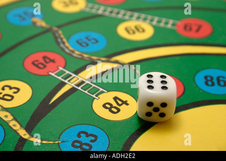 dice on a snakes and ladders board game with player missing Stock Photo