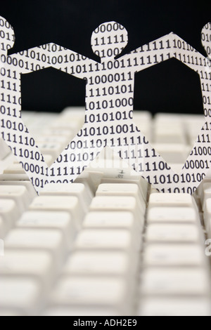 symbolic knowledge workers in the information technology industry paper dolls with binary numbers on keyboard Stock Photo