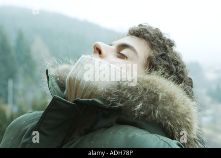 Teen boy standing outside with head back and eyes closed, mountain in background Stock Photo