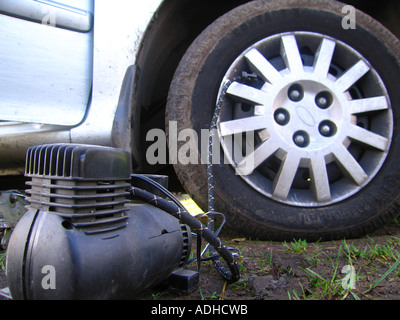 Car tyre being inflated with portable 12 volt compressor Stock Photo