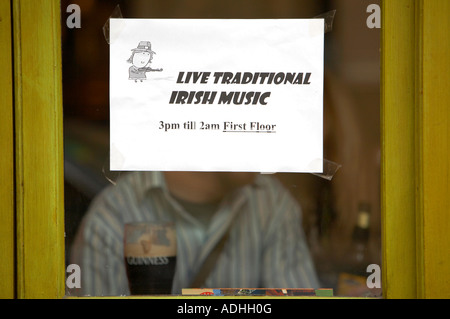 live traditional irish music 3pm till 2am first floor laser printed sign taped to window of pub in dublin with half drunk pint Stock Photo