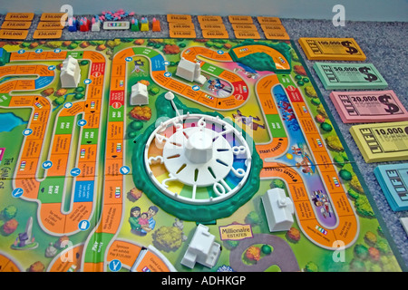 'The Game of Life' by Milton Bradley. The game board & all its' pieces, such as the money & cards, are all spread out.