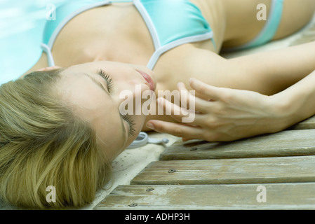 Young woman lying by edge of pool Stock Photo