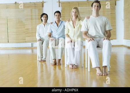 Group therapy, adults sitting in chairs with hands on each other's shoulders Stock Photo