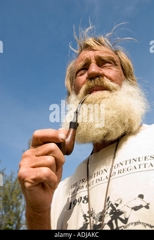 GREATER EXUMA BAHAMA GEORGE TOWN Mature man in full beard puffing on burled pipe while sailng in the Bahamas Stock Photo