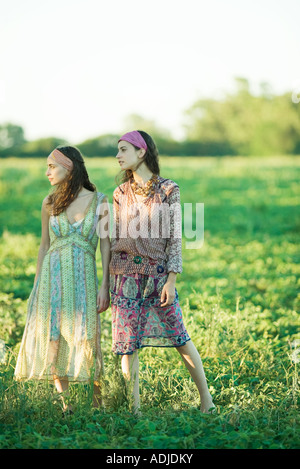 Young hippie women standing in field, looking away, full length Stock Photo