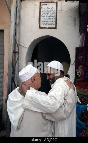 Men greating each other in front of a mosque Marrakech Morocco Stock Photo