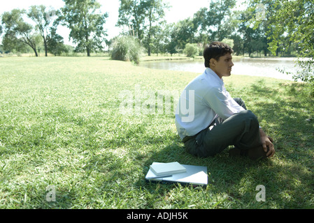 Businessman sitting on grass, laptop closed by side Stock Photo