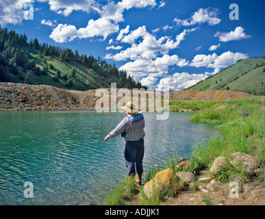 Fly fisherman casting to trout on pond in Sawtooth National Recreation Area Idaho Stock Photo