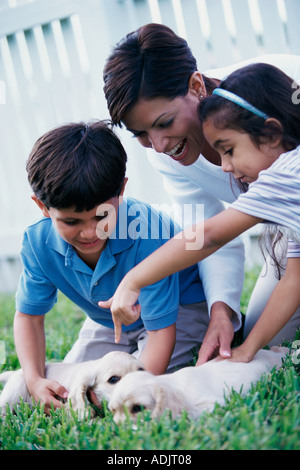 Mother with her son and daughter playing with puppies Stock Photo