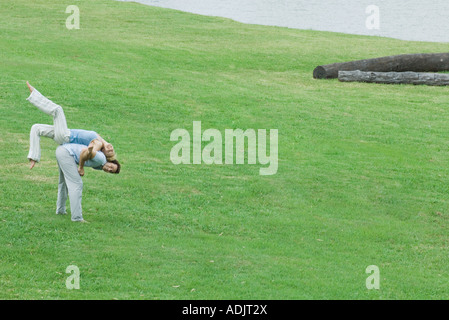 Man bending over with woman on back, on lawn Stock Photo