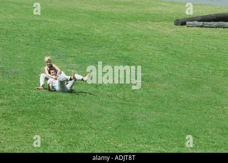 Couple sitting on grass together, man leaning back on woman Stock Photo