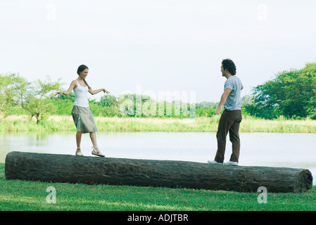 Couple standing on log, approaching each other Stock Photo