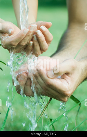Couple cupping hands under running water Stock Photo