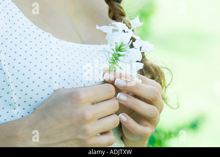 Woman holding flower, close-up of hands and chest Stock Photo