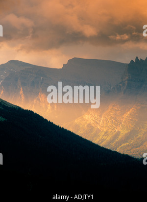 Sun peeking through clouds and shining on mountains of Glacier National Park Montana Stock Photo