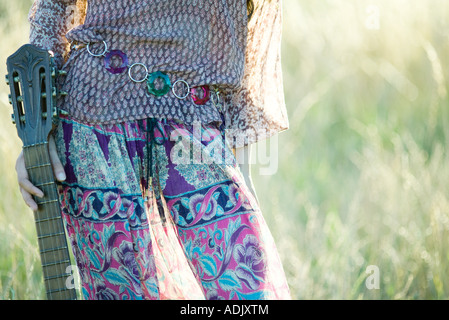 Young hippie woman holding guitar, cropped view of mid section Stock Photo
