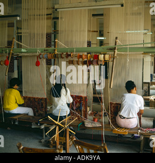 Silk Carpet Factory with three women working skillfully at looms with their backs to the camera in Shanghai China Stock Photo