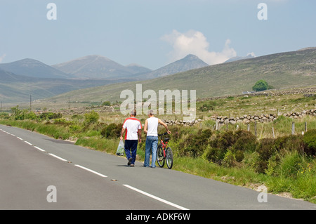 Two men walk the country road north from Attical in the southern Mourne Mountains, County Down, Ireland. Stock Photo
