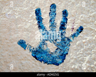 'Silhouette of child's hand covered in 'blue paint' on 'white wall', USA'. Stock Photo