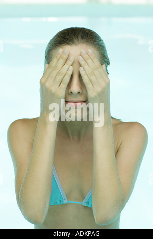 Young woman in swimsuit, hands over face Stock Photo
