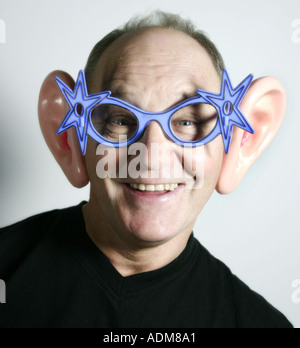 Man aged sixty dons a silly pair of glasses and ears Stock Photo