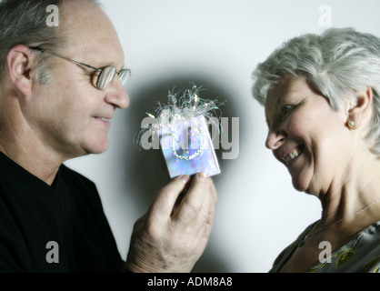 Couple in their sixties Man gives woman a small wrapped present Stock Photo