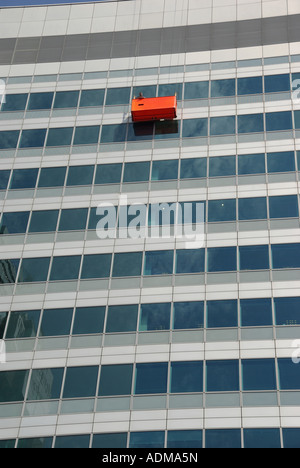 London workmen in cradle slung from roof carrying out work to curtain wall cladding on office block Stock Photo