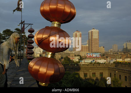 Young woman looking over the ramparts of the South Gate Pavilion and the modern city, Xian, Shaanxi, China. Stock Photo