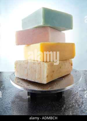 4 bars of scented hand made soap piled on an aluminium soap dish.  Bathroom Toiletries Stock Photo